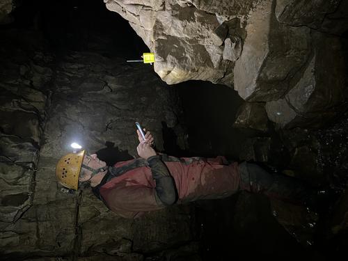 A caver reading message on a smartphone standing next to a relay node
